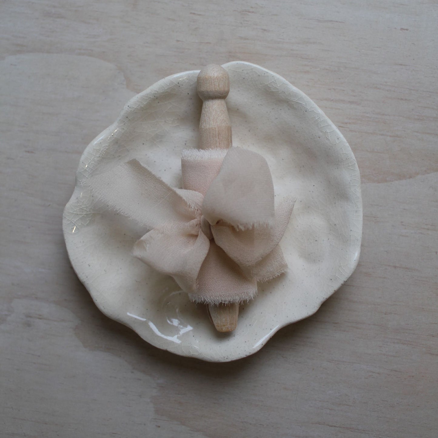 Hand-dyed pale pink silk chiffon ribbon rolled neatly, displaying its natural color variations and soft crepe texture