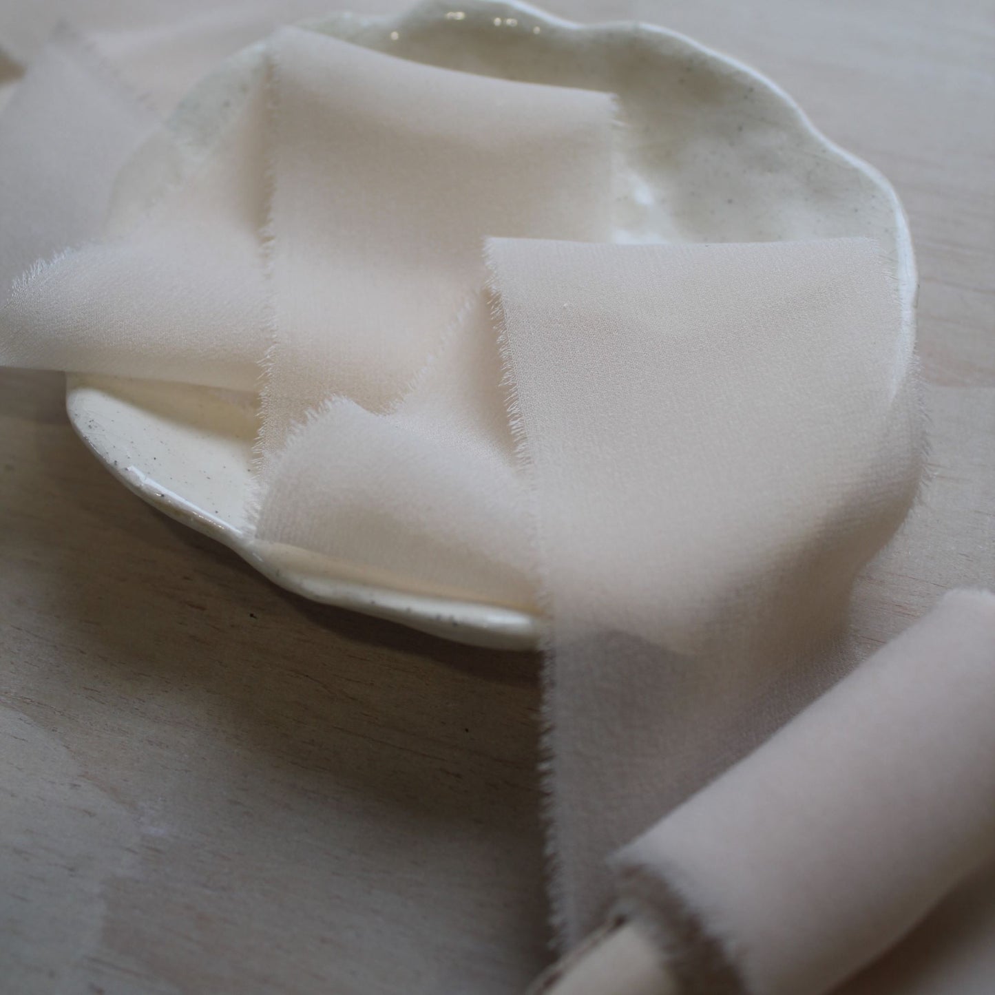 Close-up of soft, sheer silk chiffon ribbon in blush pink, highlighting its delicate frayed edges