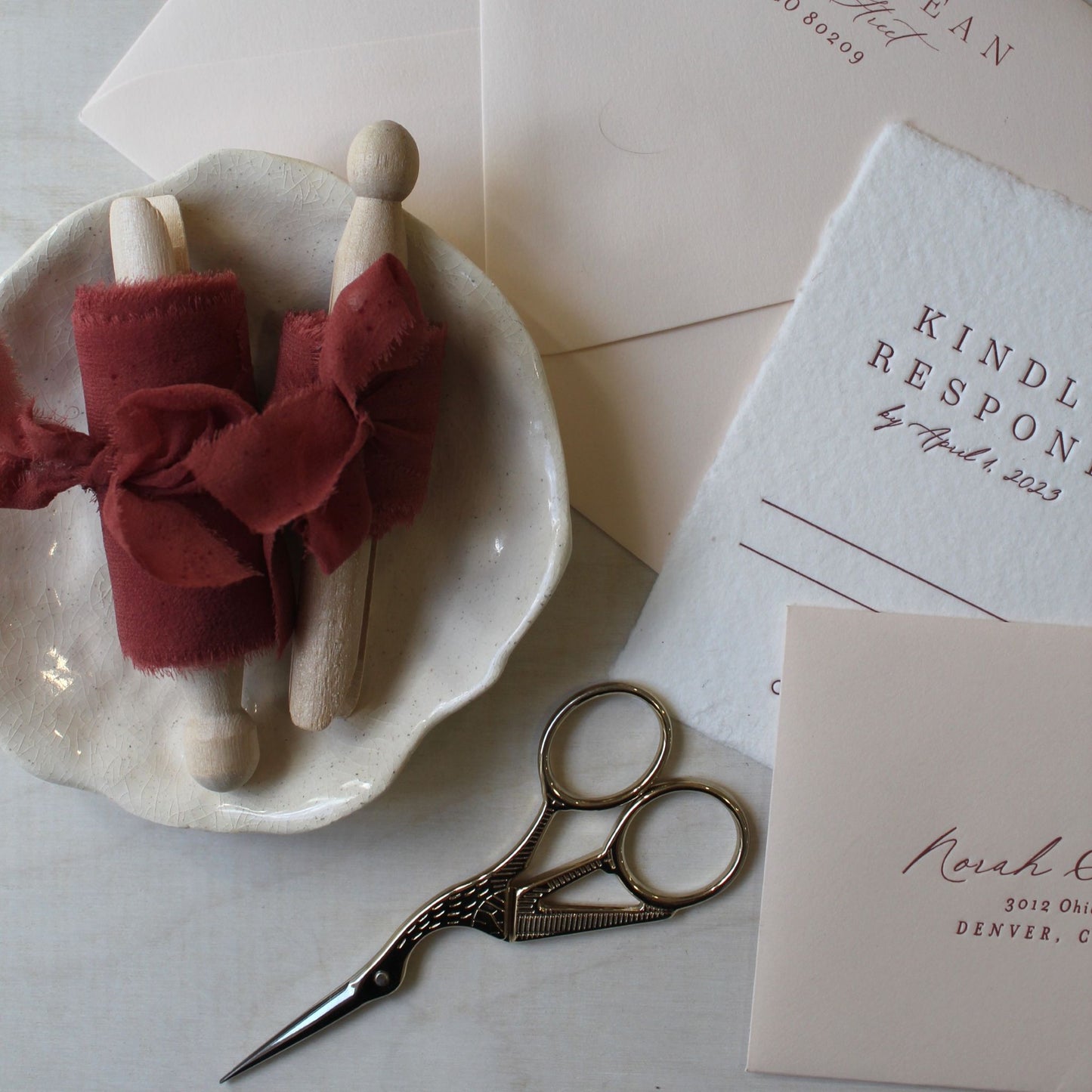 Earth-toned red silk ribbon styled in a flat lay with wedding details.