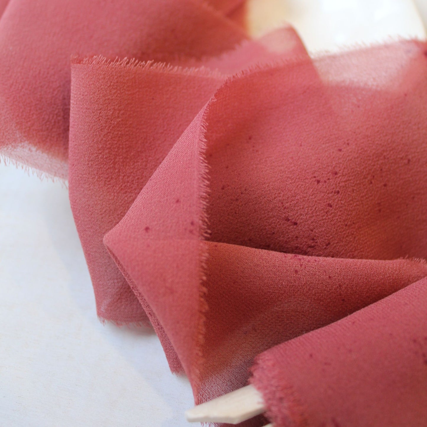 Close-up of hand-torn red rust chiffon
