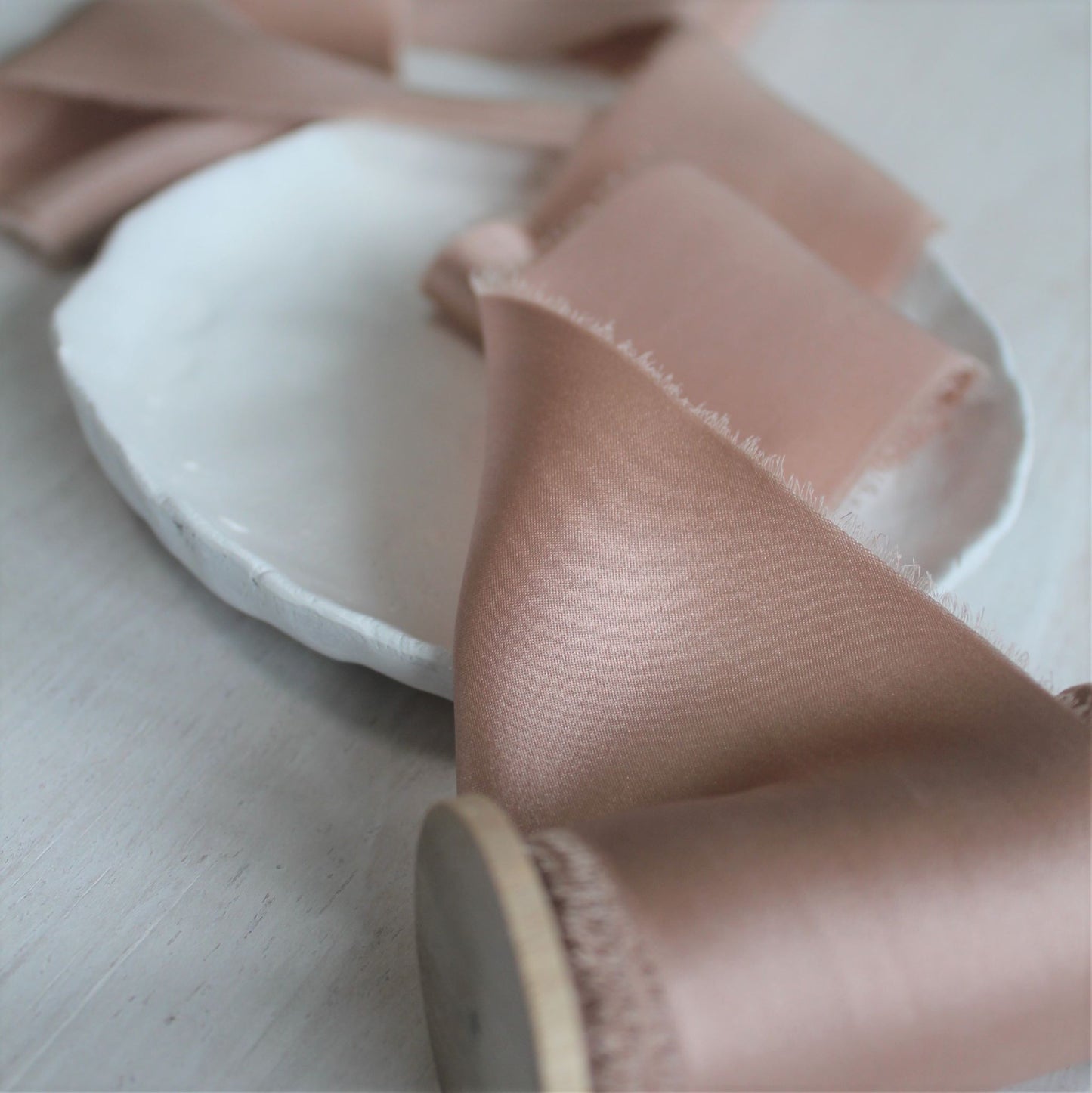 Close-up of hand-torn dusty rose silk charmeuse ribbon showcasing feathered edges.