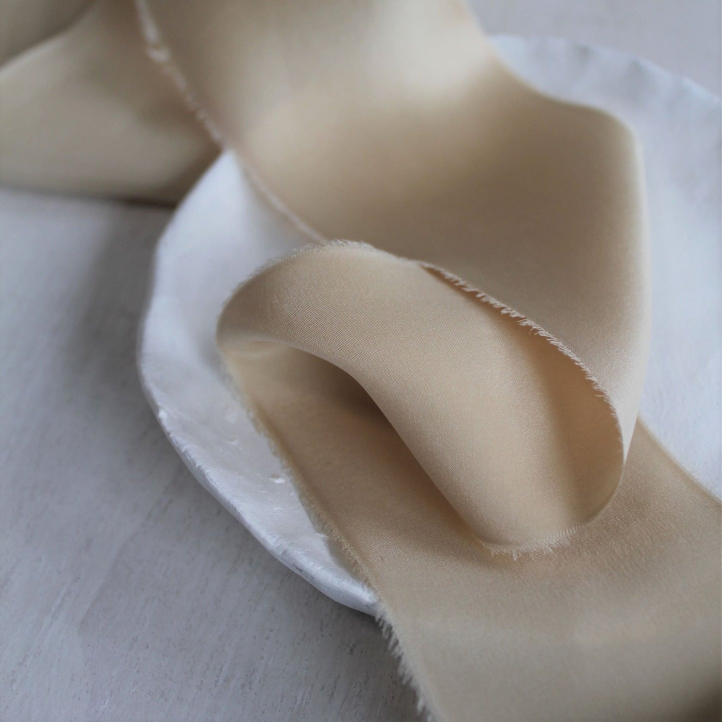 Feathered edge of the maple silk charmeuse ribbon, showing its delicate texture and natural dye.