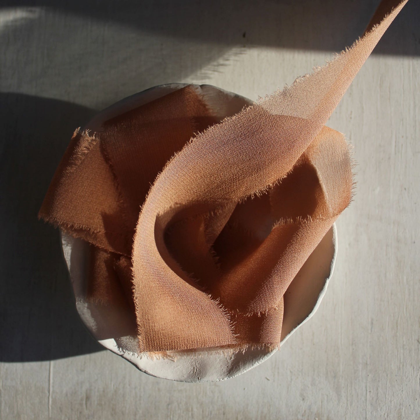 Terra cotta silk chiffon ribbon softly curled to show its sheer texture