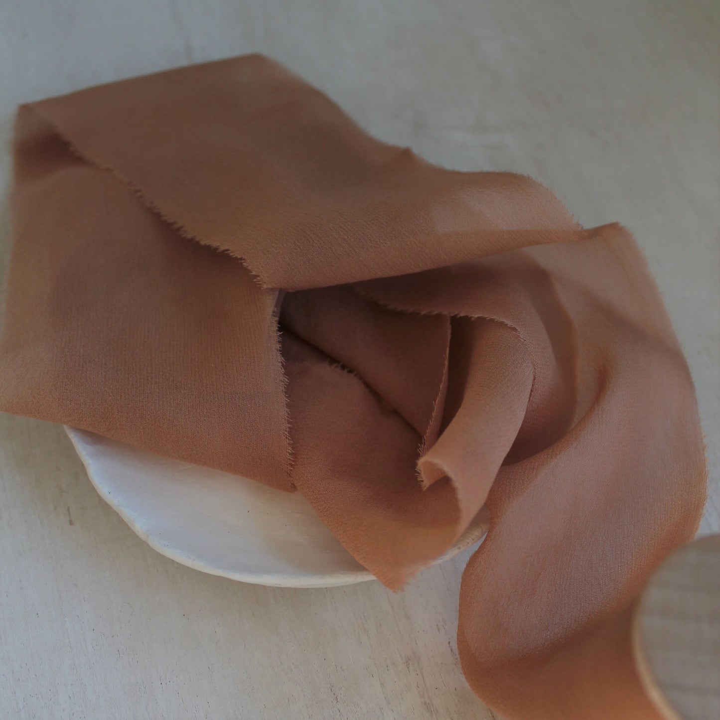 Lightweight rust-coloured silk chiffon ribbon on white background
