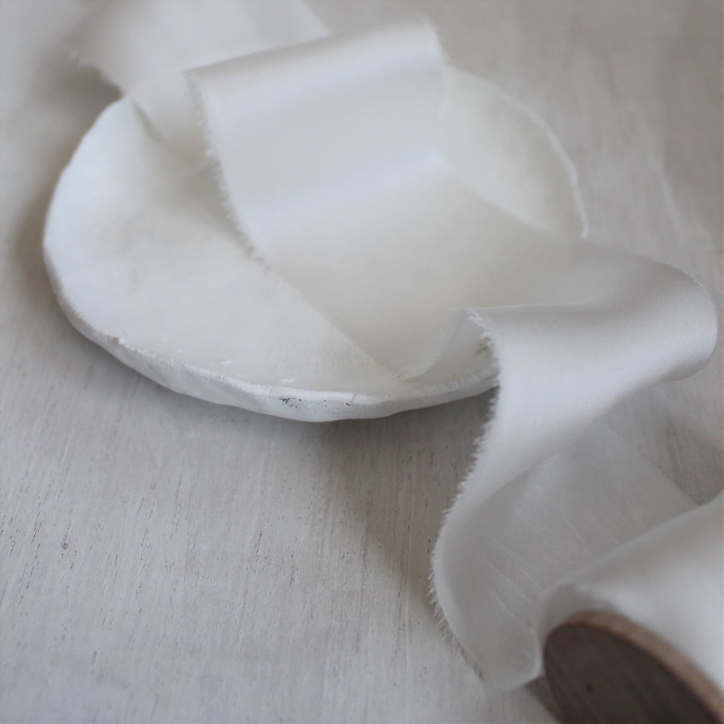 white silk ribbon with torn edges displayed in a soft, airy light, perfect for wedding styling