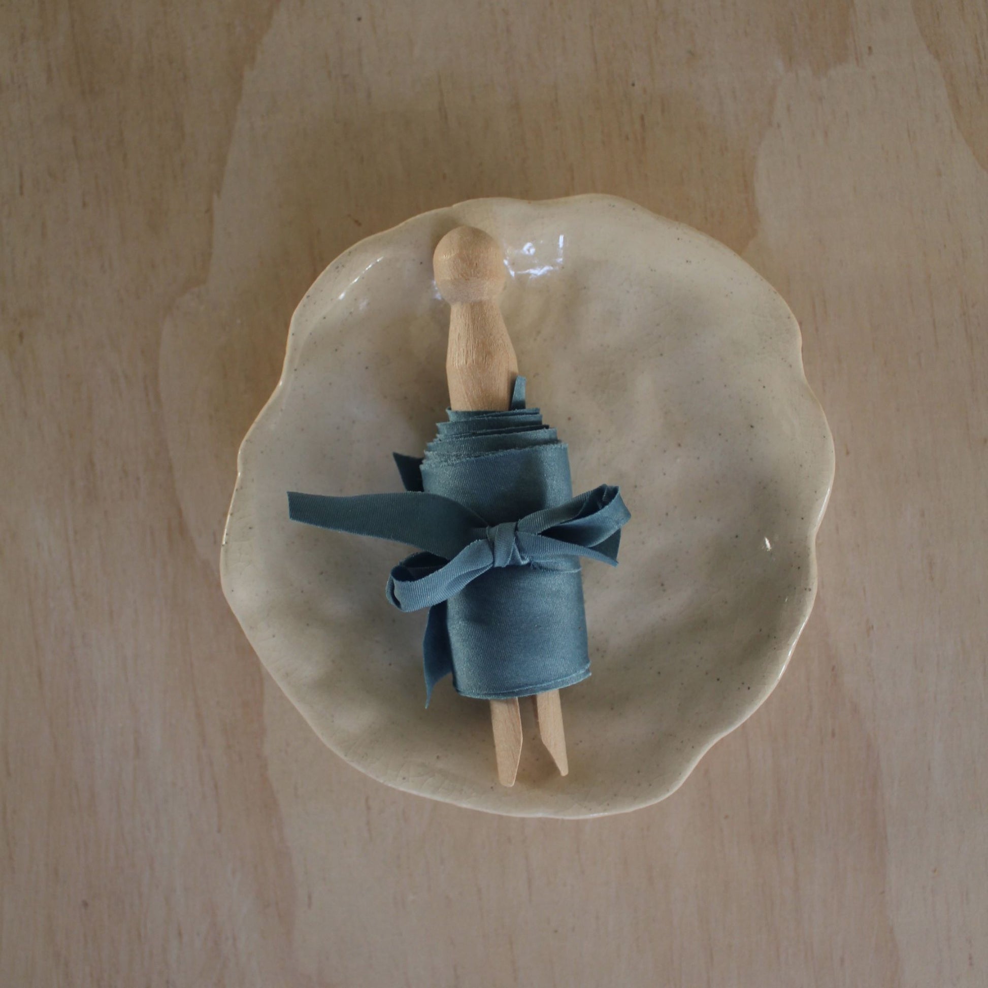 Luxury blue silk ribbon bias cut, handmade in Canada, displayed on a ceramic plate, perfect for weddings and stationery.