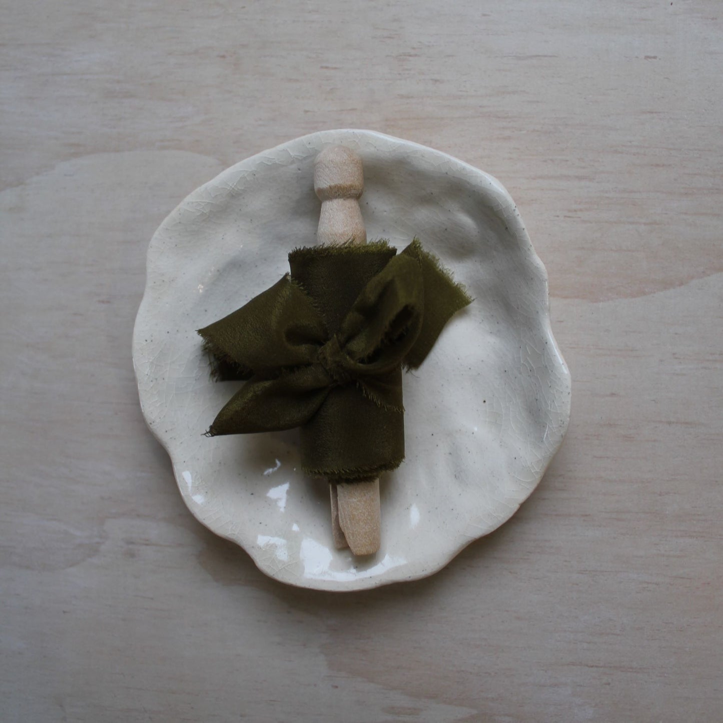 Hand-dyed moss green silk ribbon coiled neatly on a wooden spool