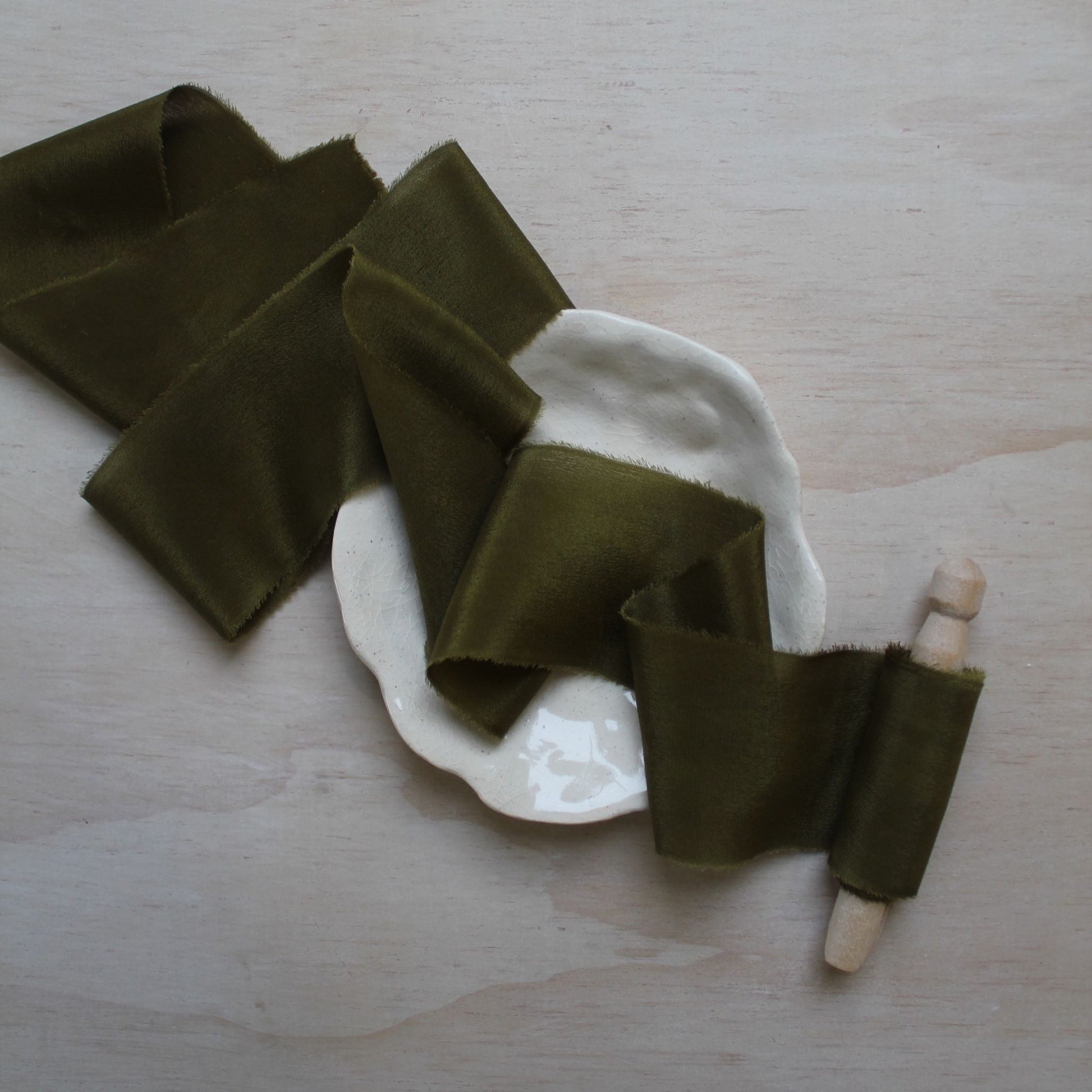 Moss green silk ribbon laid flat, emphasizing its subtle sheen and organic feel.
