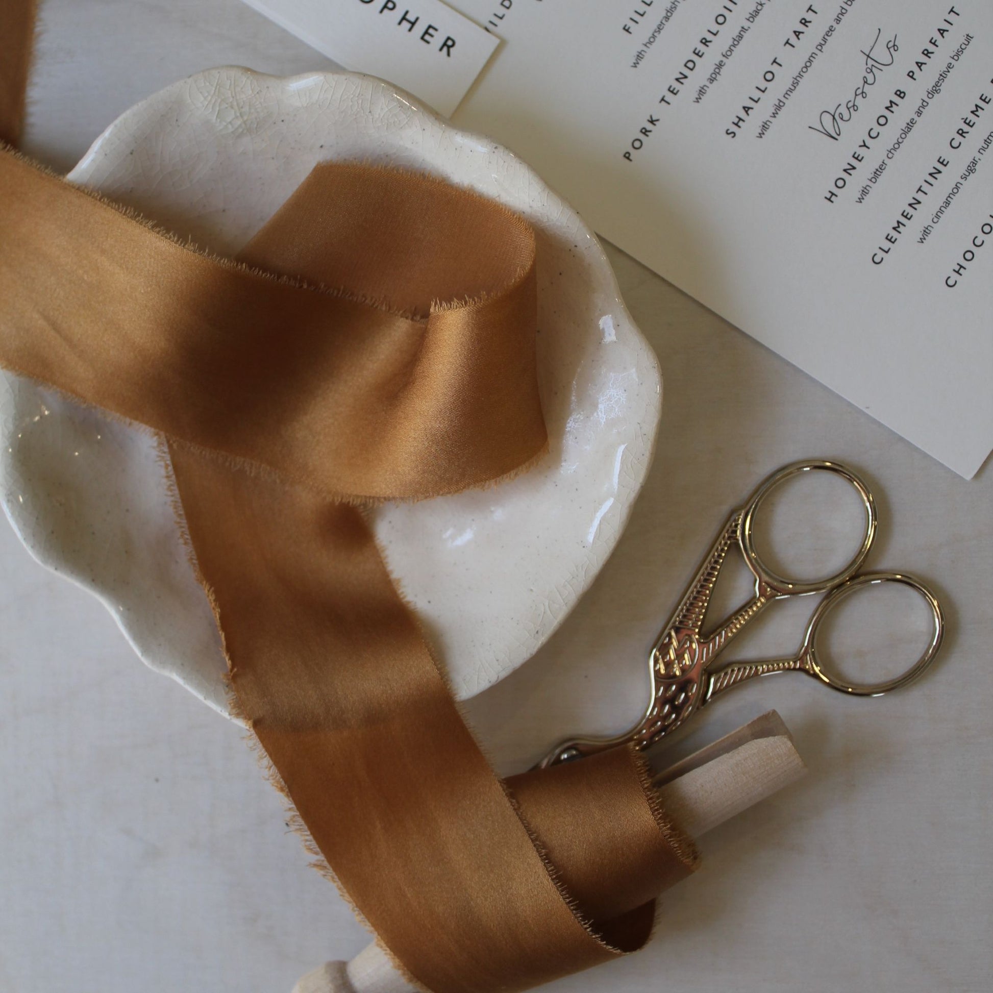 TERRA COTTA charmeuse silk hand dyed ribbon on a plate, perfect for wedding floristry, flat lay styling, and stationery.