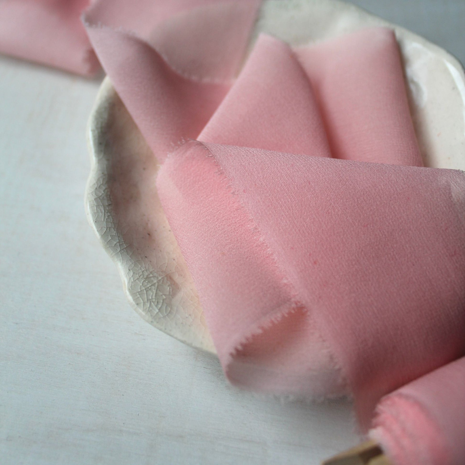 Soft iridescent pink chiffon ribbon with a delicate hand-torn finish, ideal for creating romantic wedding decor and invitations.