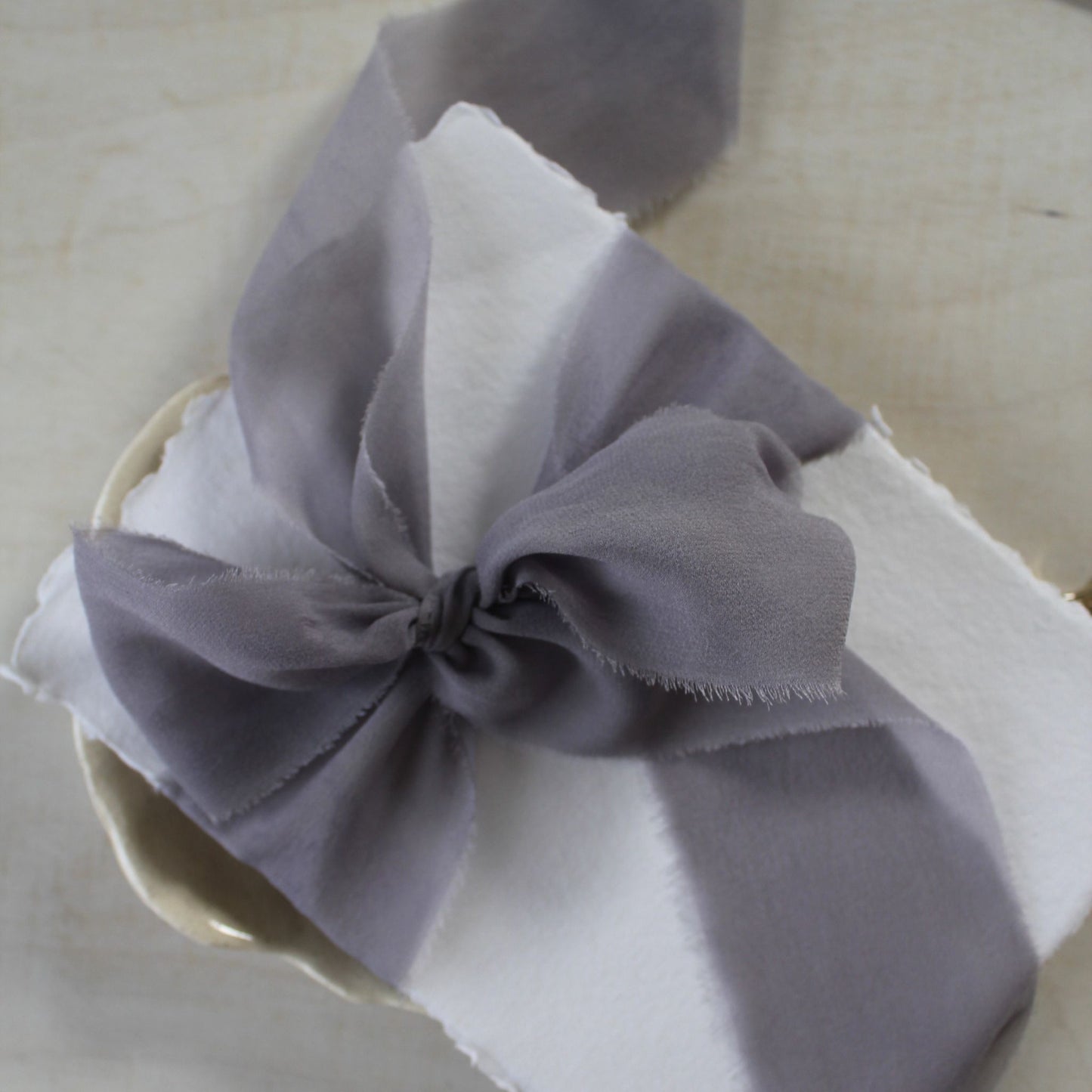 Silk chiffon ribbon in Lavender Mist color wrapped around wedding stationery in a bow