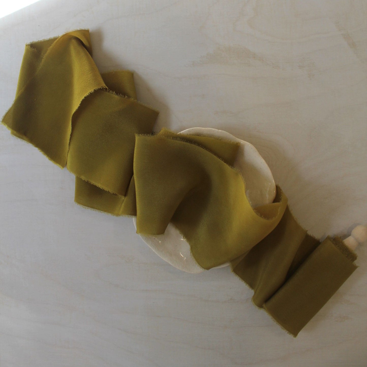 Hand-dyed chartreuse silk ribbon styled on a wood surface