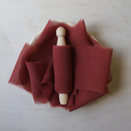 lose-up of hand-torn red rust chiffon silk ribbon, naturally dyed wood clothes peg
