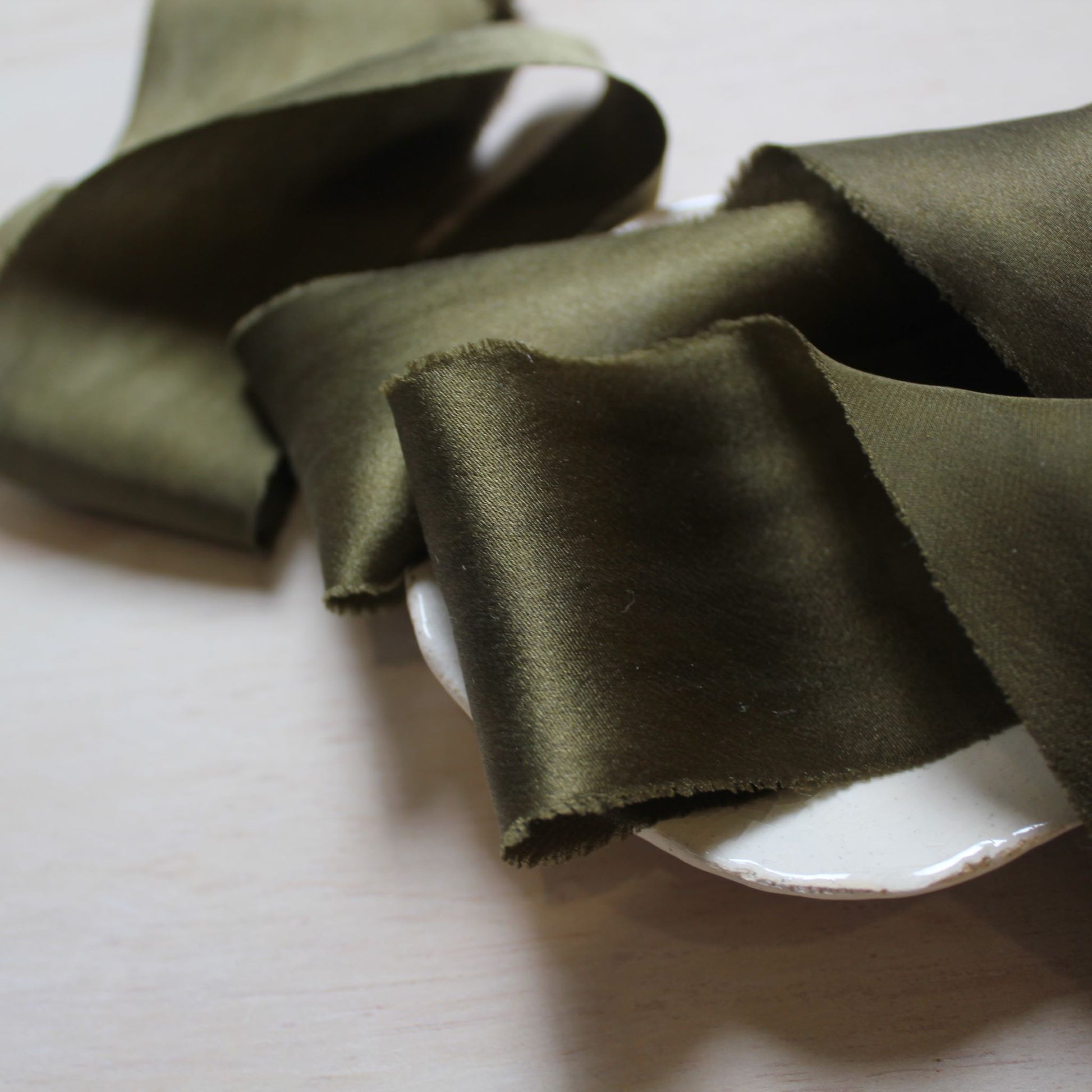 Close-up of hand torn dark green silk ribbon edge