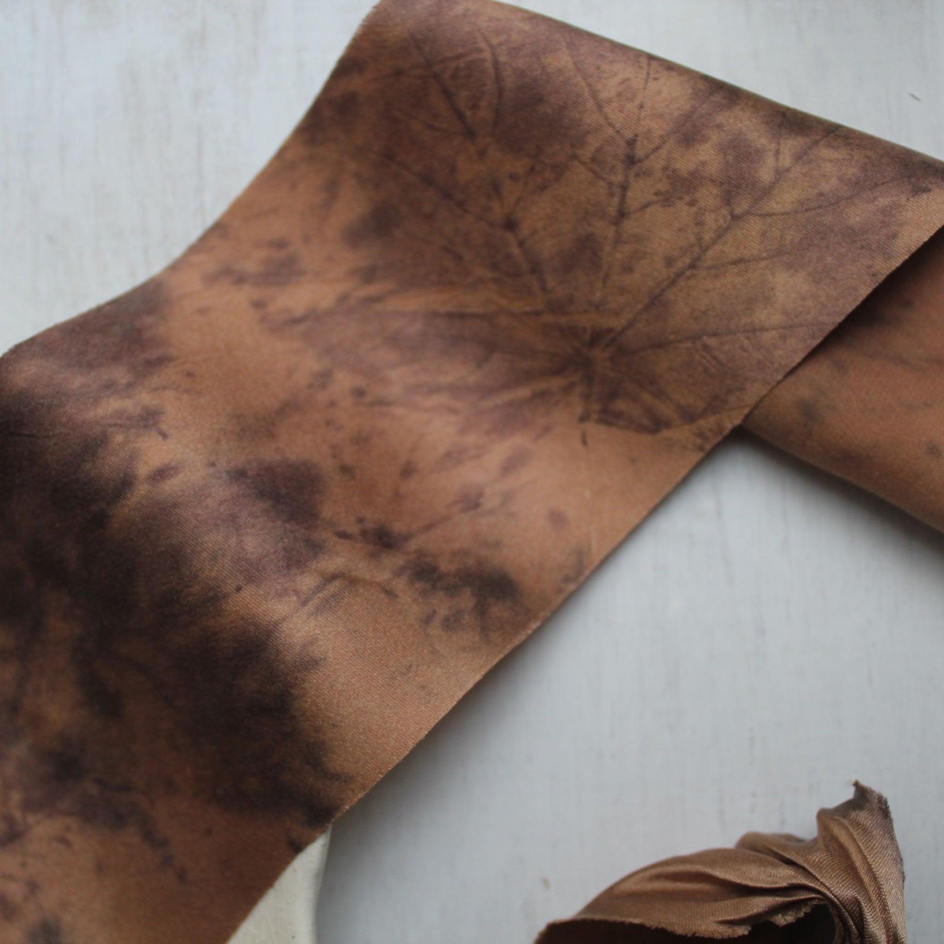 Leaf printed silk ribbon styled around wedding invitation