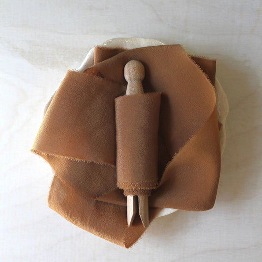 Terra cotta silk crepe ribbon styled on wood background
