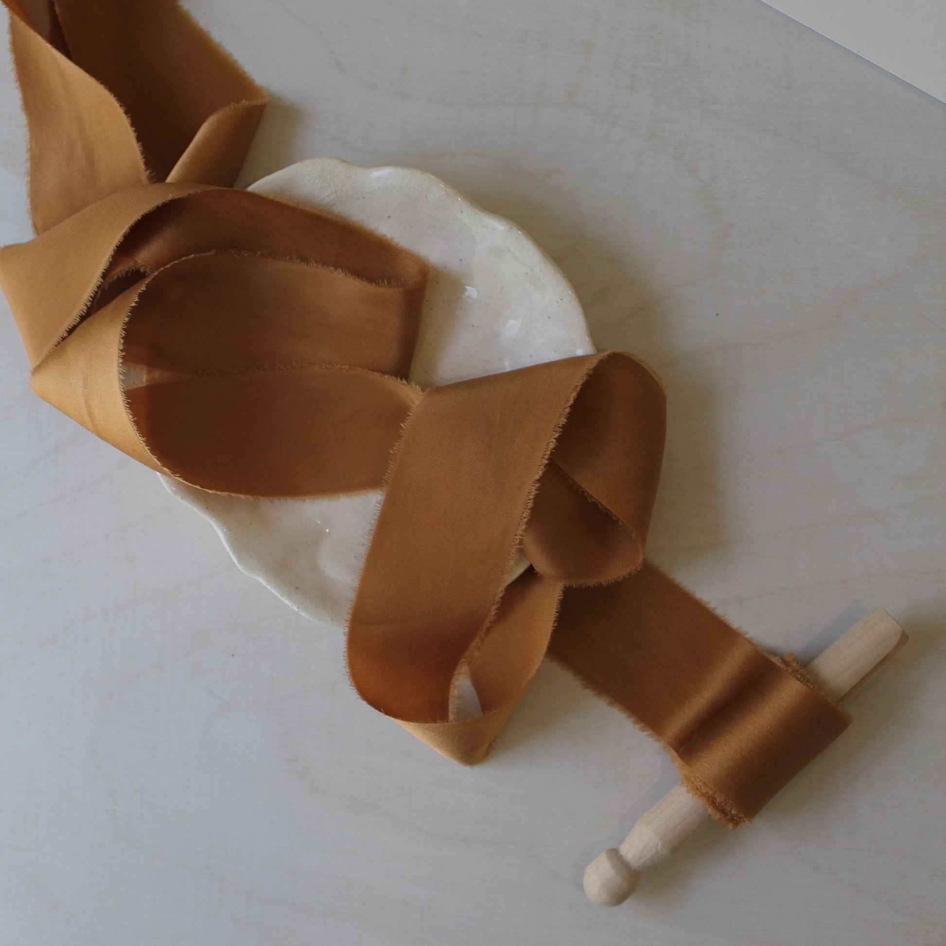 TERRA COTTA charmeuse silk hand dyed ribbon on a plate, perfect for wedding bouquets and styling.