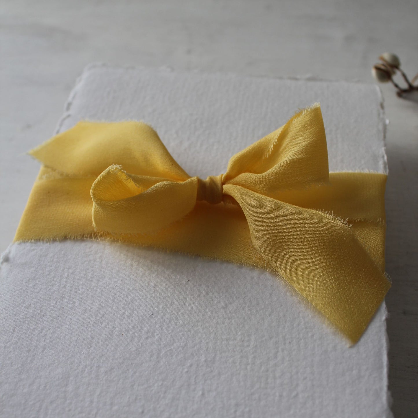 yellow crepe ribbon tied around handmade paper in a bow