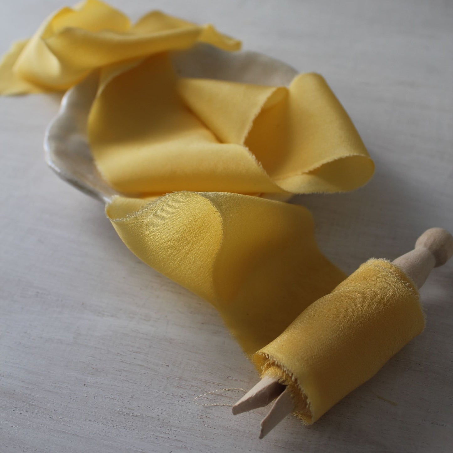 Hand-dyed yellow buttercup silk ribbon wound on a wooden clothespin – naturally dyed in Toronto, Canada
