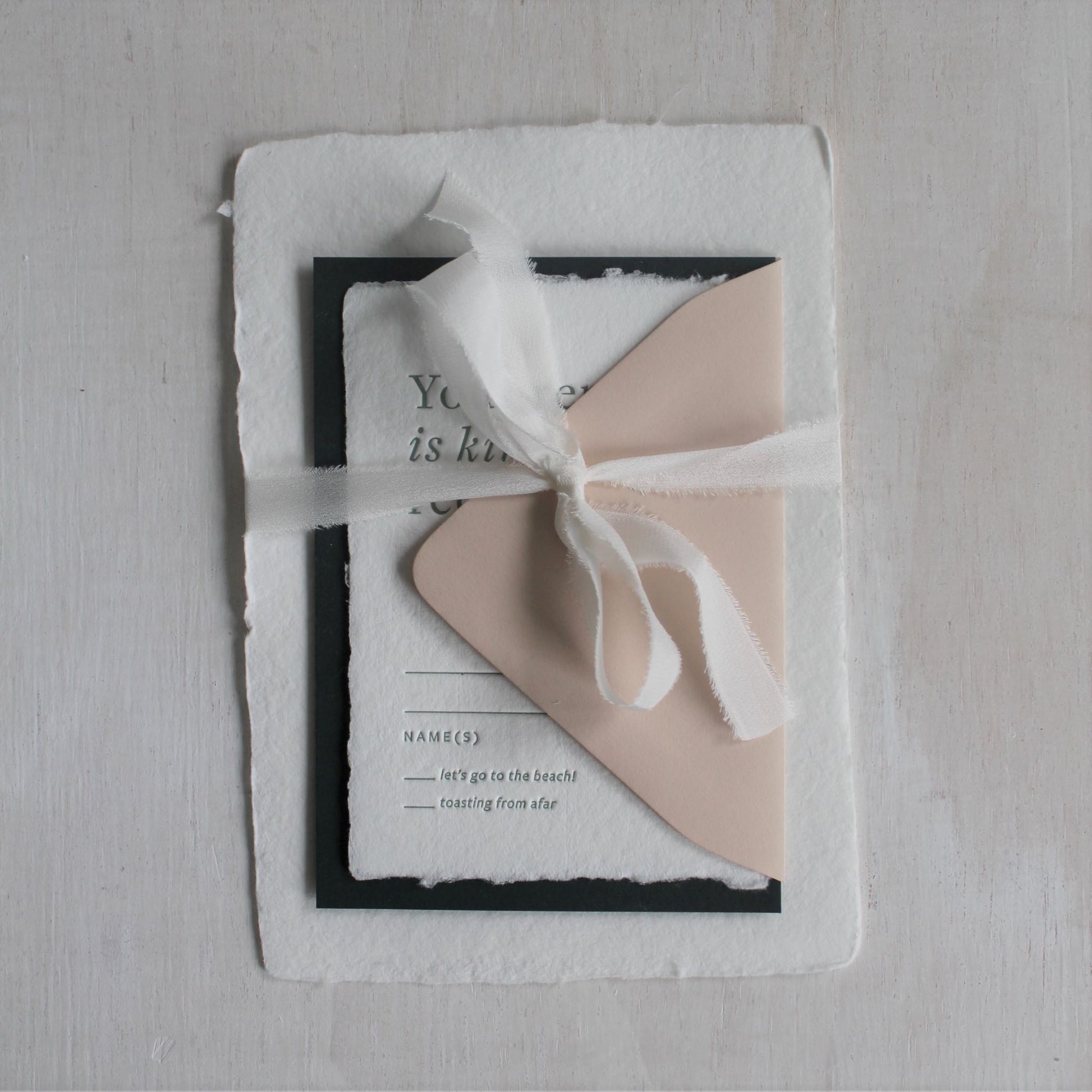 Hand-torn-white-0.5-inch silk ribbon styled on wedding invitation