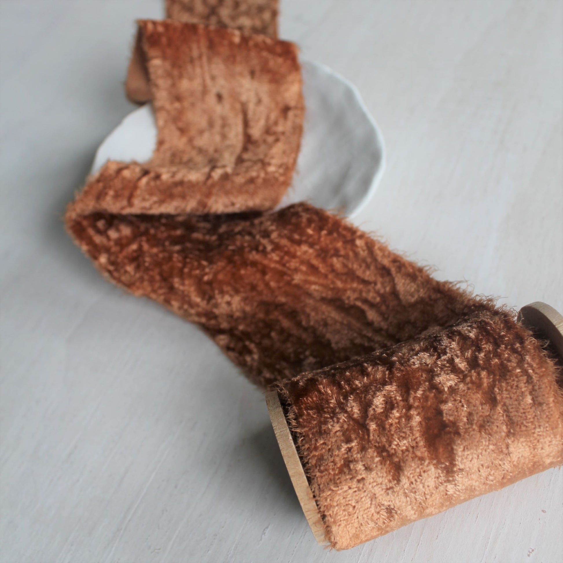 Close-up of frayed edge on terra cotta silk velvet ribbon