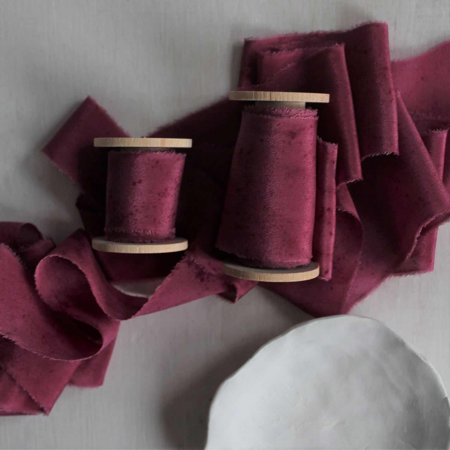 Berry silk ribbon used in wedding stationery, offering a luxurious touch for invitations and envelopes.