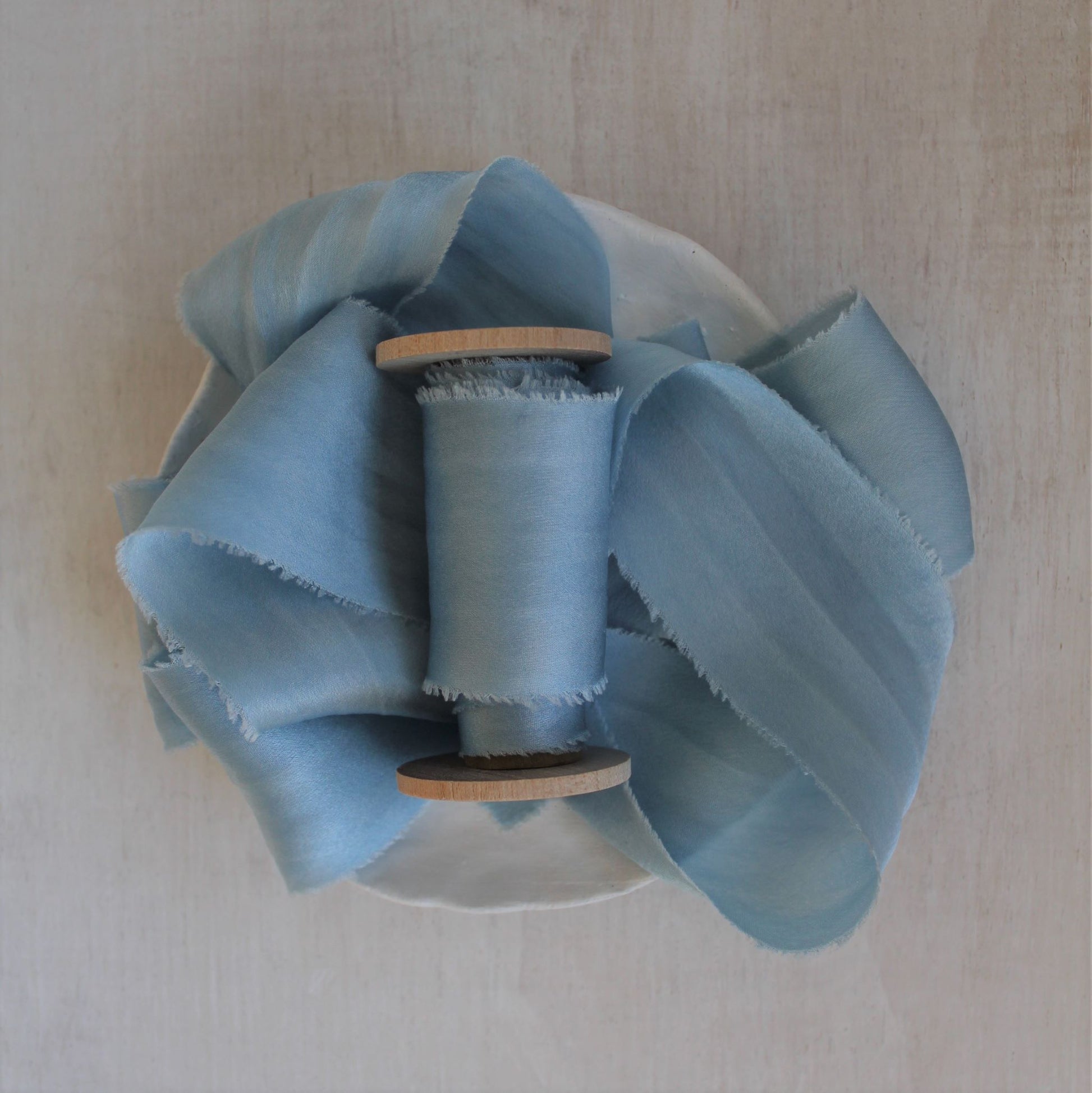 Pale blue silk charmeuse ribbon, hand-cut on the bias, elegantly draped to showcase its soft sheen and fluidity