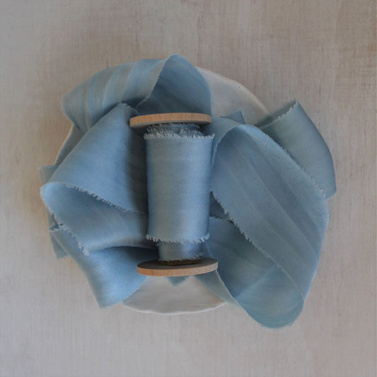 Pale blue silk charmeuse ribbon, hand-cut on the bias, elegantly draped to showcase its soft sheen and fluidity
