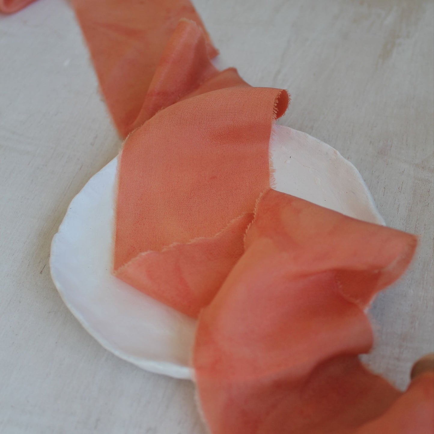 lose-up of bright pink hand-torn silk crepe de chine ribbon showing soft, textured surface.