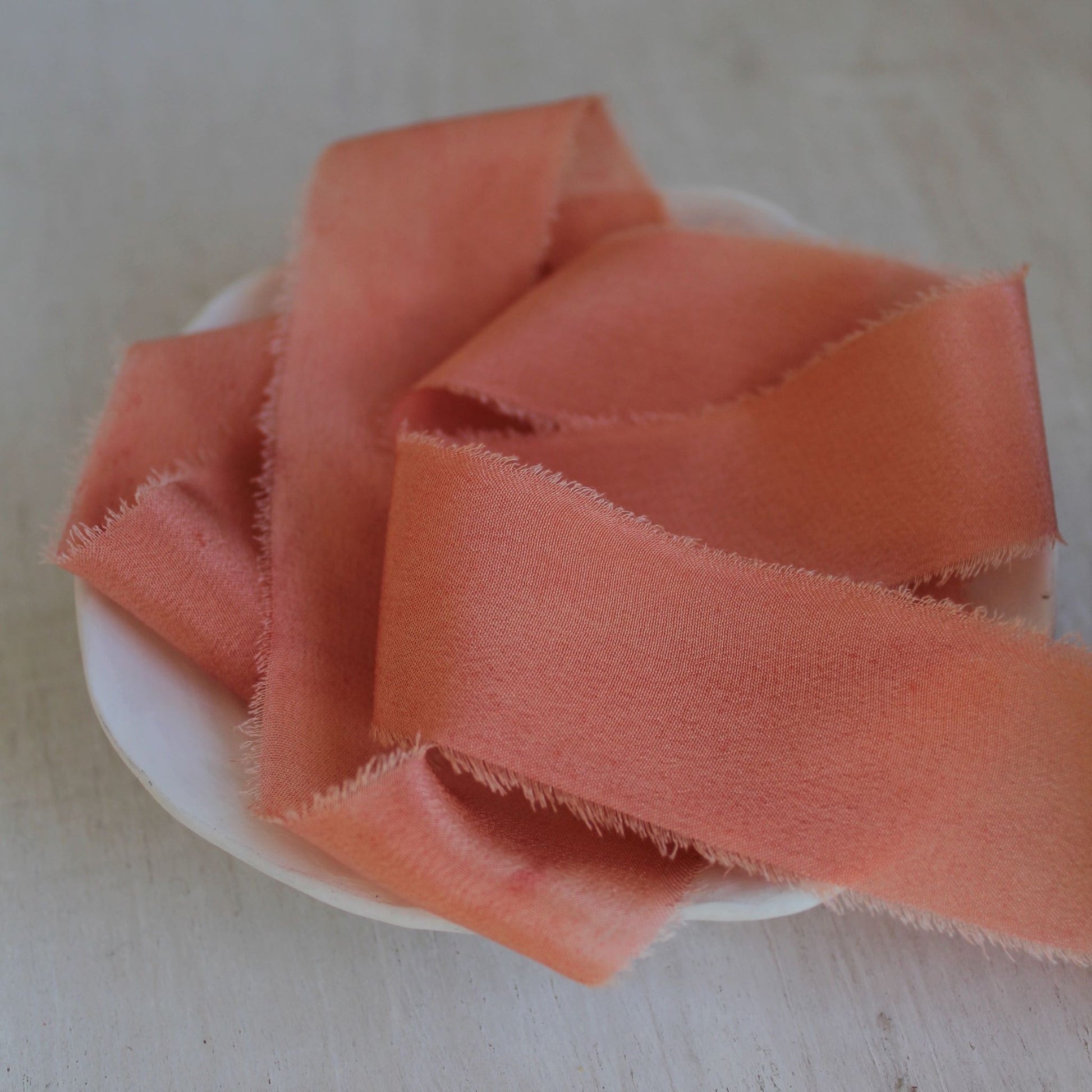 Bright pink silk crepe de chine ribbon with a hand-torn edge, dyed with natural dyes for an eco-friendly touch.