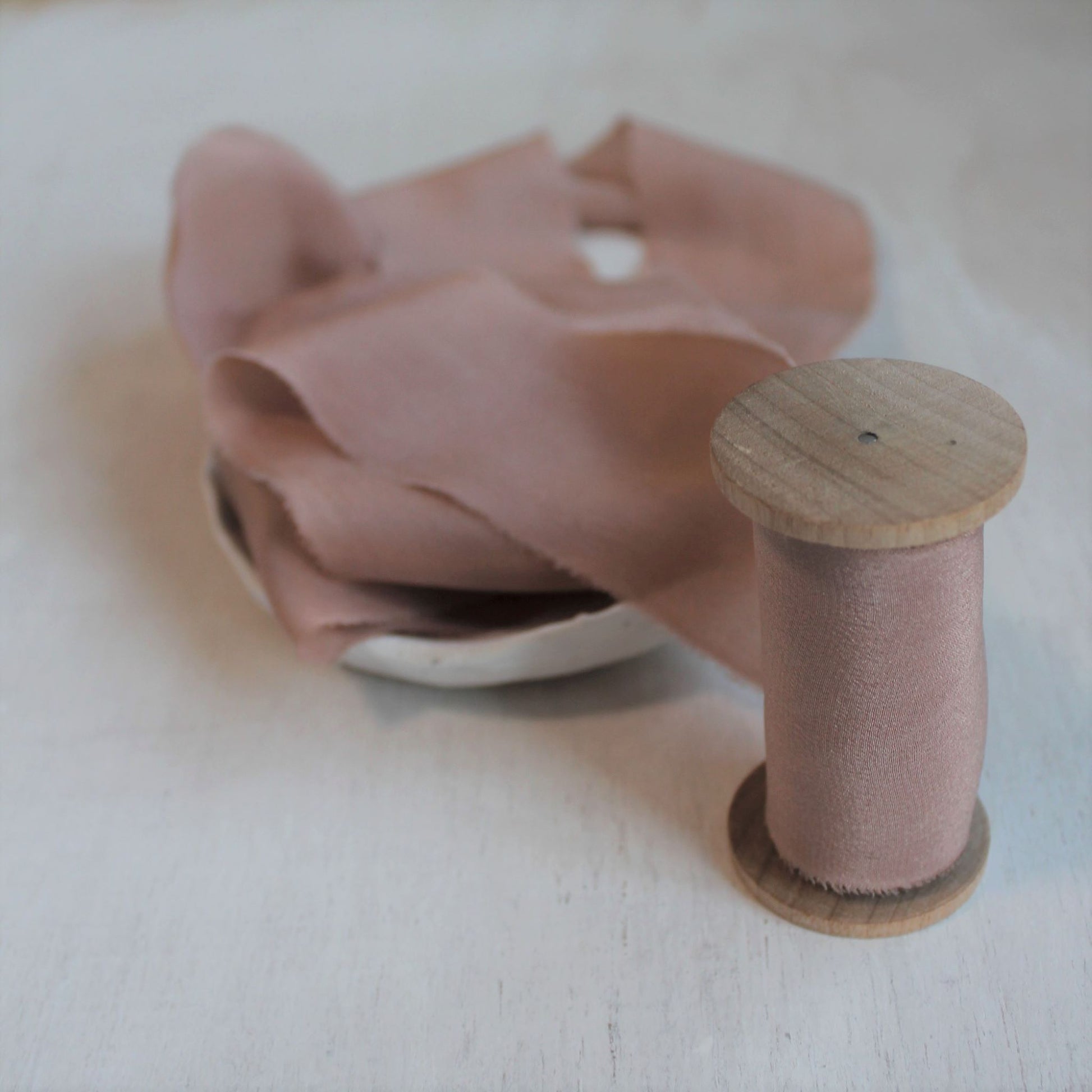 Hand-torn crepe de chine silk ribbon in dusty rose on wood spool