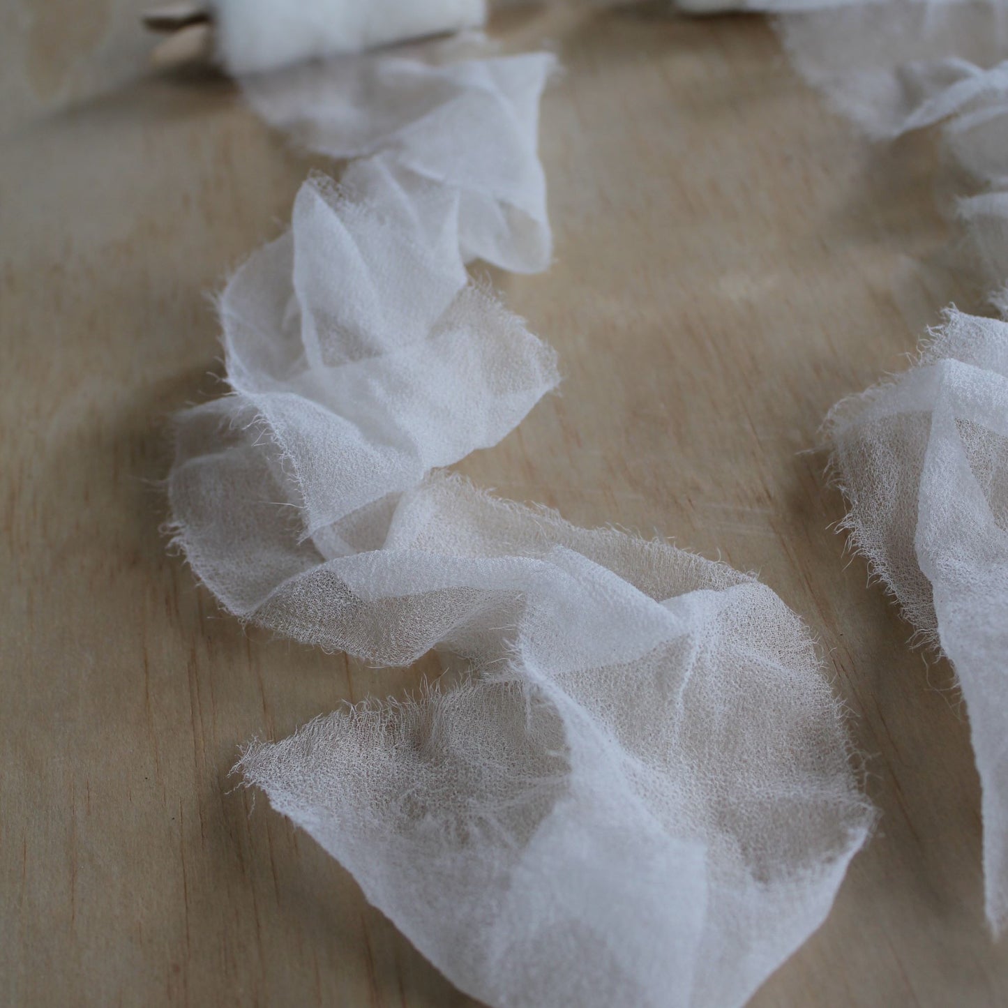 Close-up of hand-torn edge of white silk chiffon ribbon