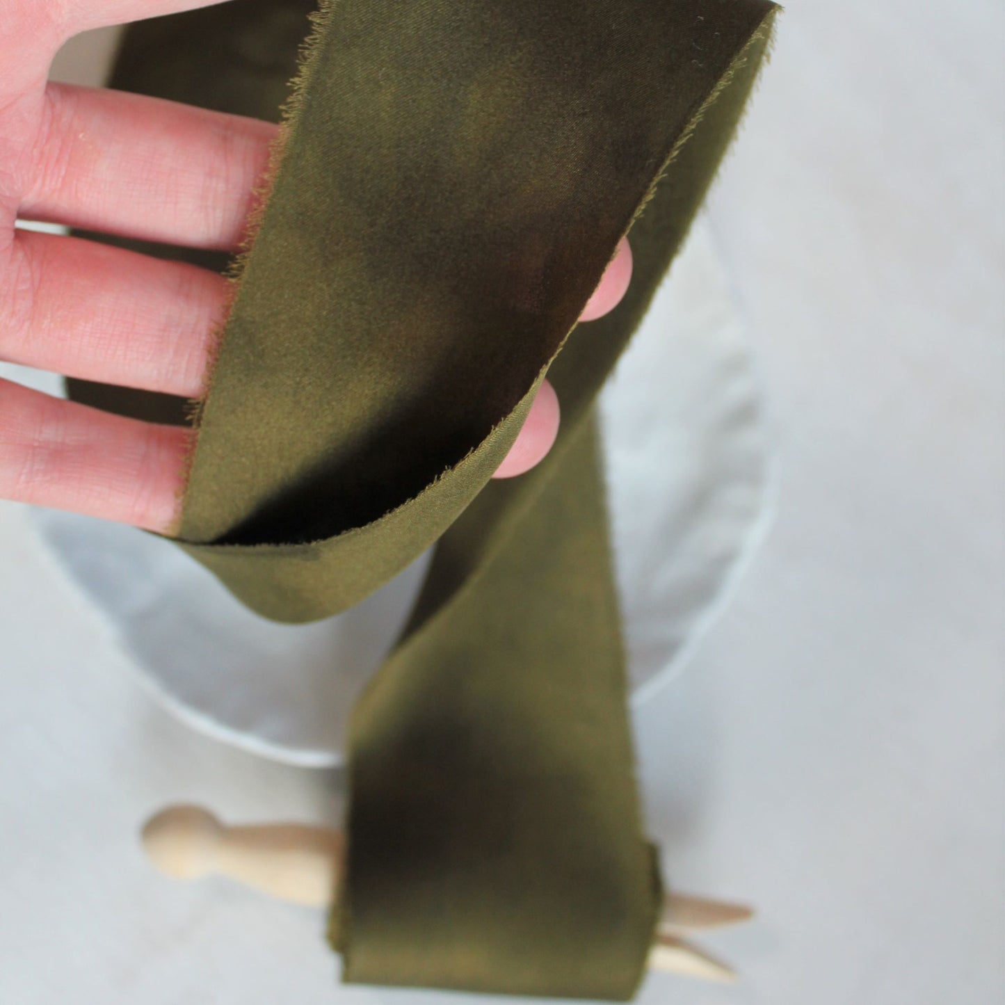 Close-up of hand-torn dark moss silk charmeuse ribbon 