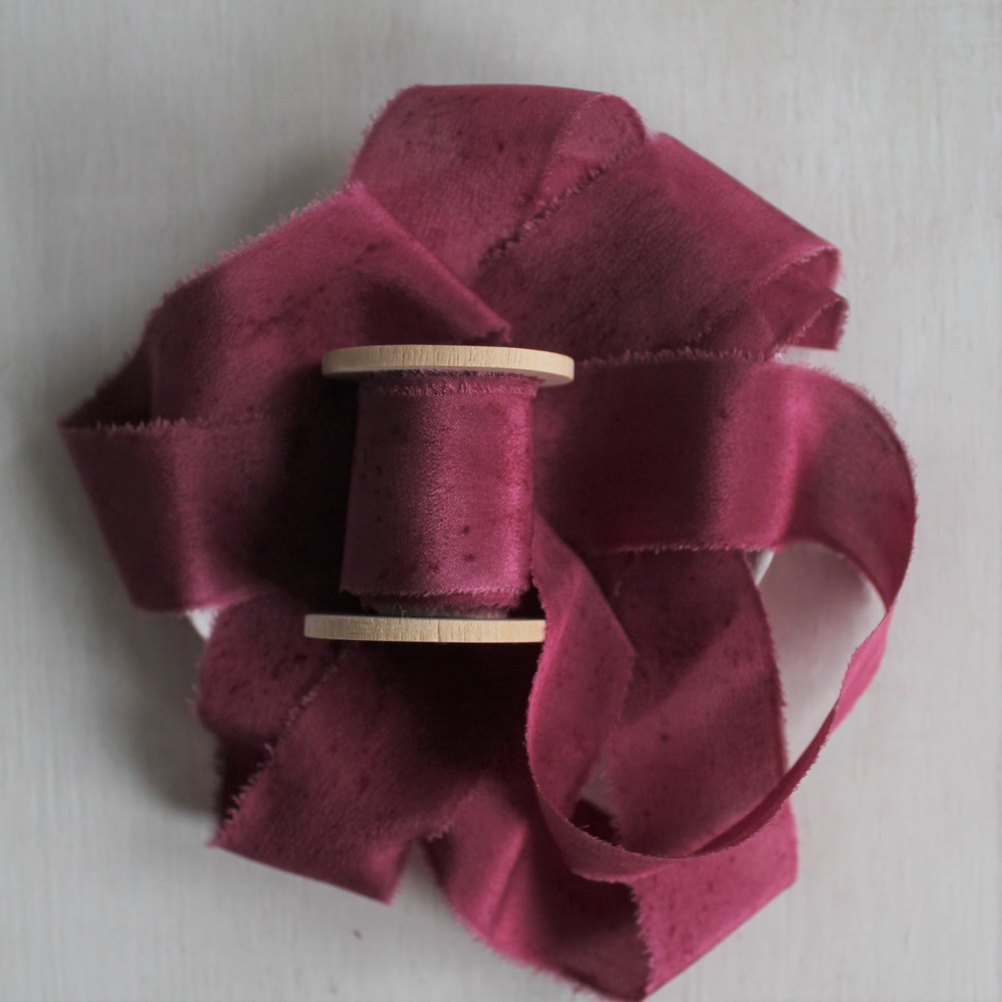 Close-up of hand-torn berry silk ribbon, showcasing its rustic edge and natural texture.