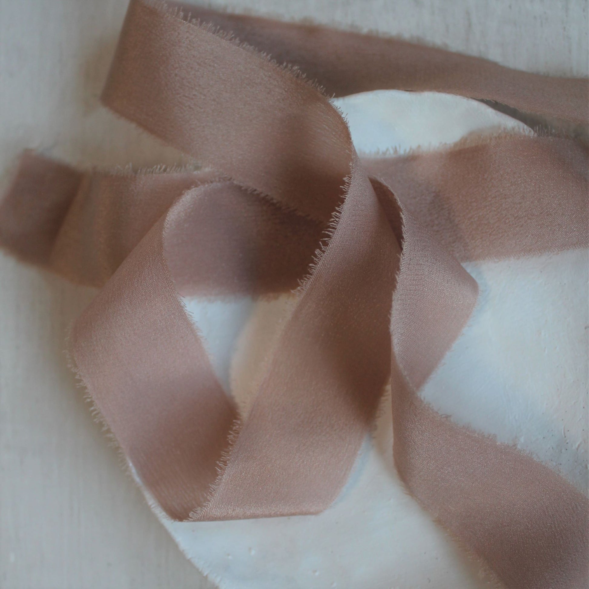 Close-up of soft pink ribbon showing delicate frayed edge