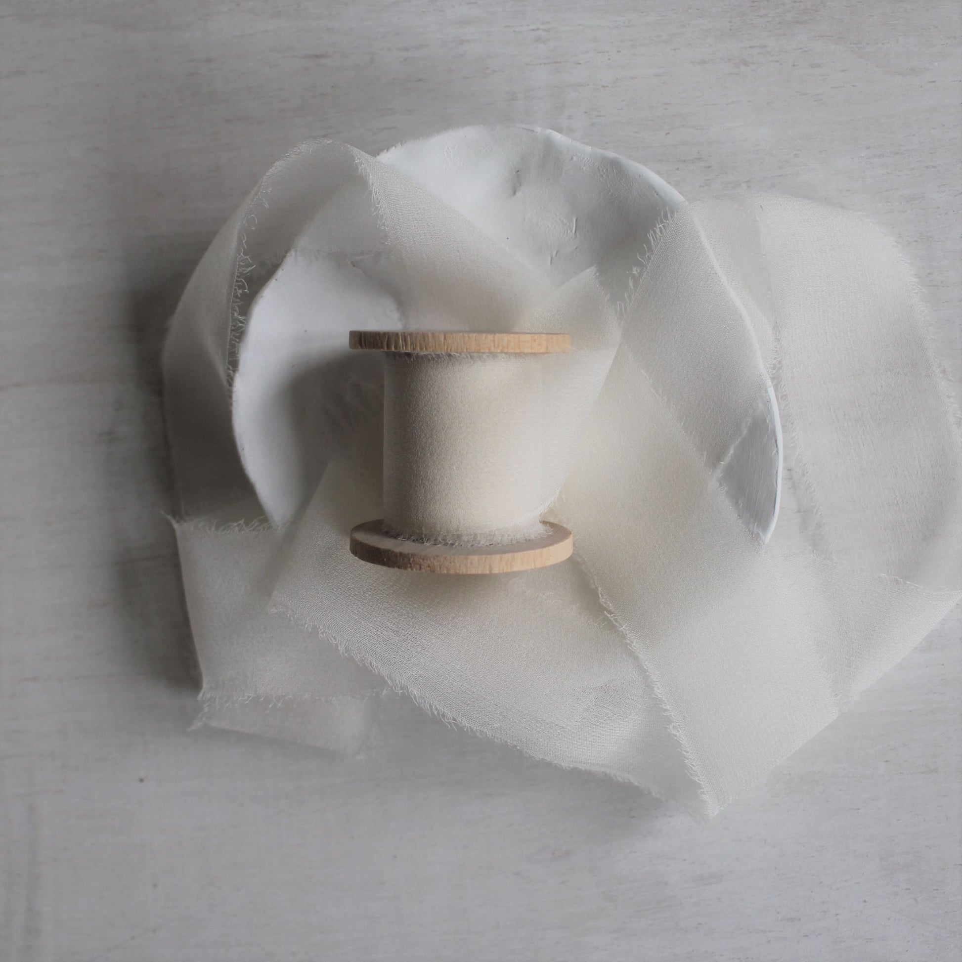 White silk ribbon with sheer elegance and drape on wood spool