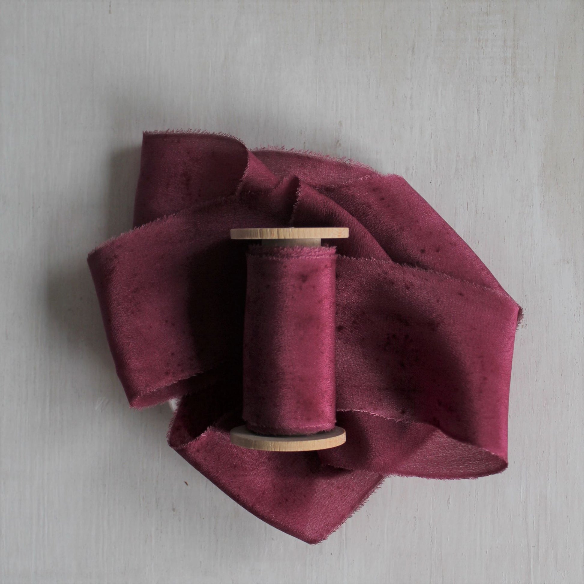 Luxe berry silk crepe de chine ribbon with hand-torn edges for bridal bouquets and table styling.