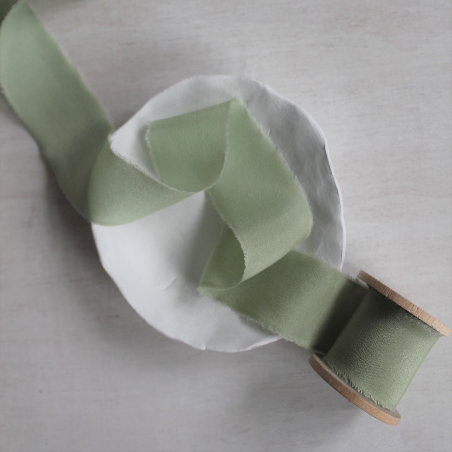 Soft green silk ribbon styled with wedding stationery