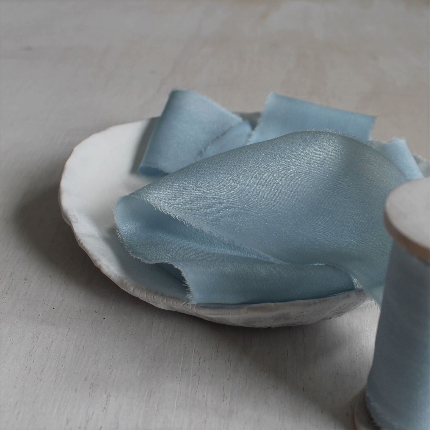 Hand-torn silk ribbon in pale blue for flatlay styling

