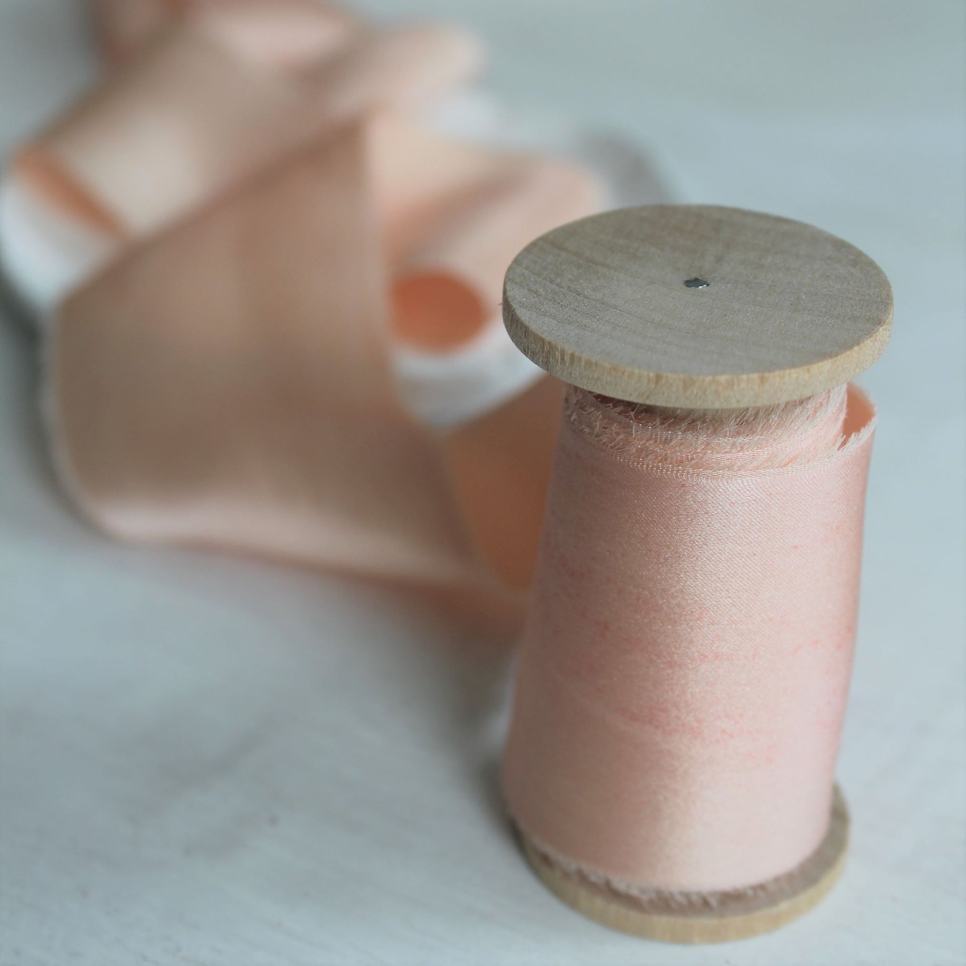 Close-up of hand-torn pink blush silk charmeuse ribbon showcasing feathered edges.