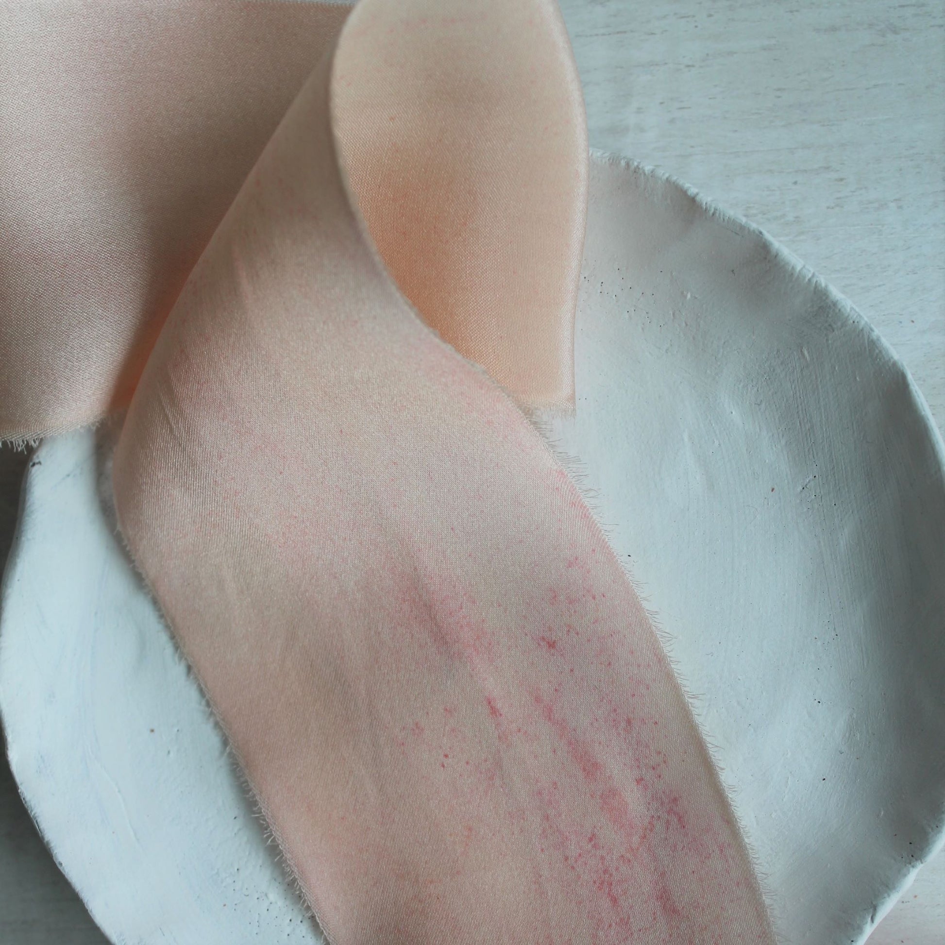 Close-up of hand-torn pink blush silk charmeuse ribbon showing natural dye marking