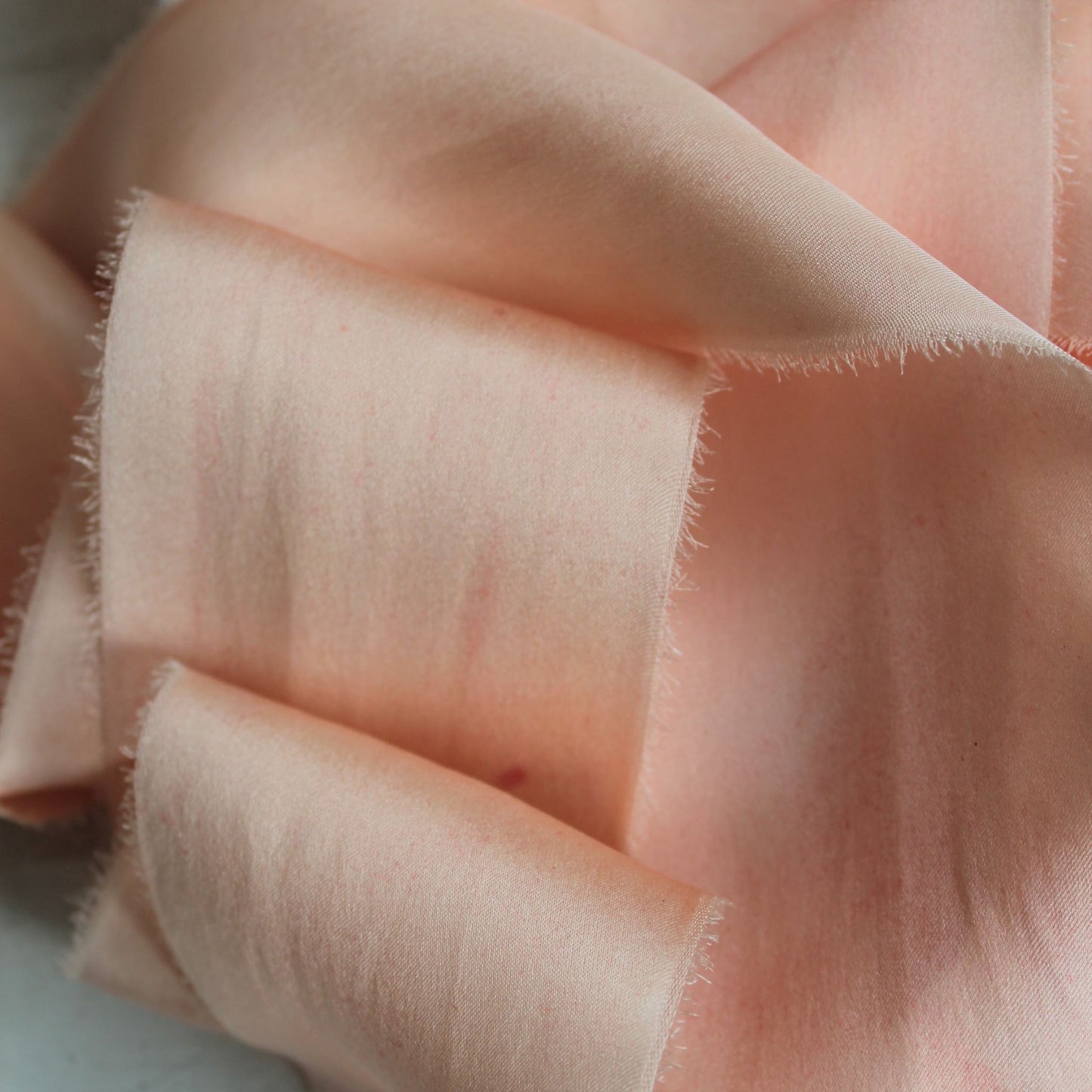 Close-up of hand-torn pink blush silk charmeuse ribbon
