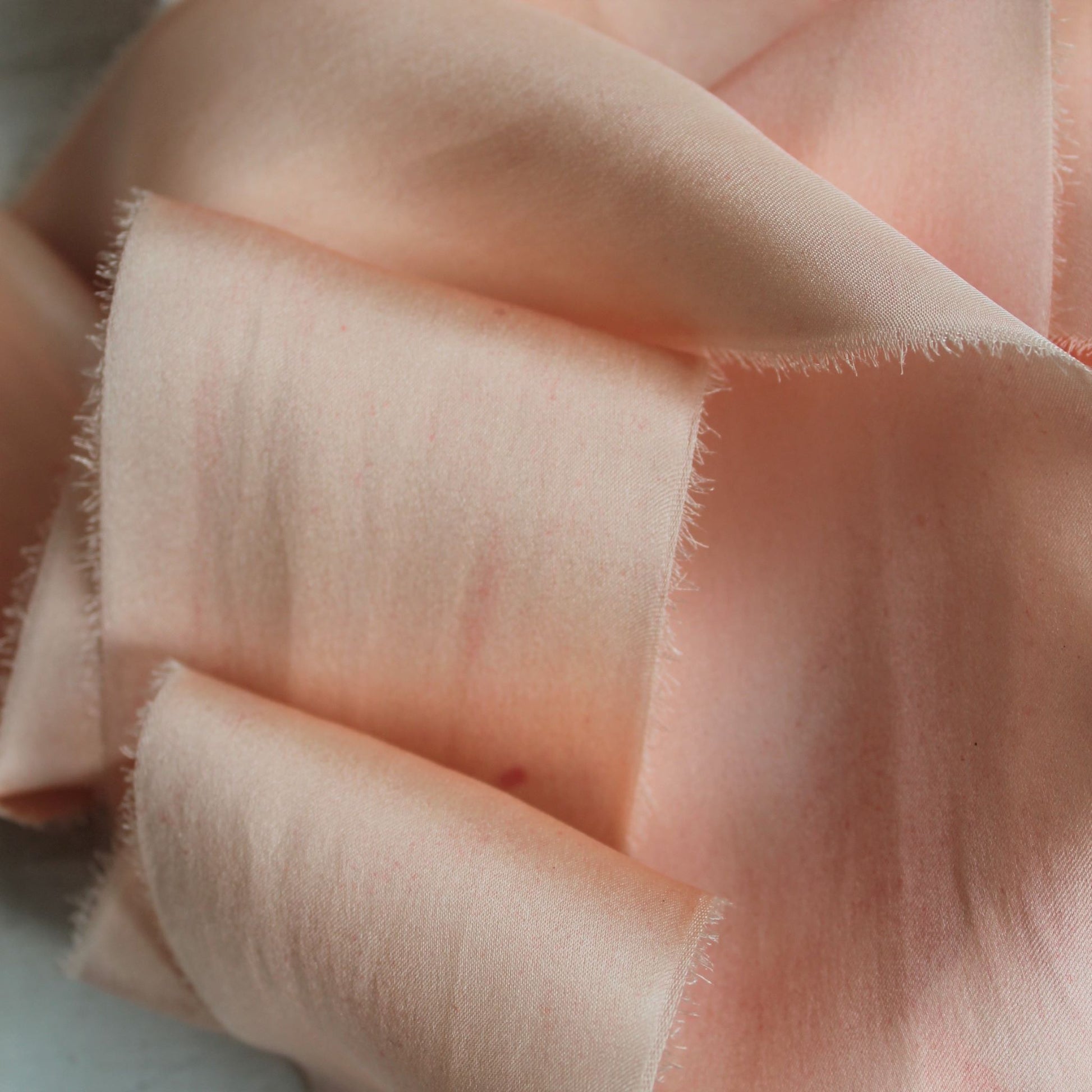Close-up of hand-torn pink blush silk charmeuse ribbon