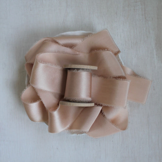 Hand-torn pink charmeuse silk ribbon on wood spool