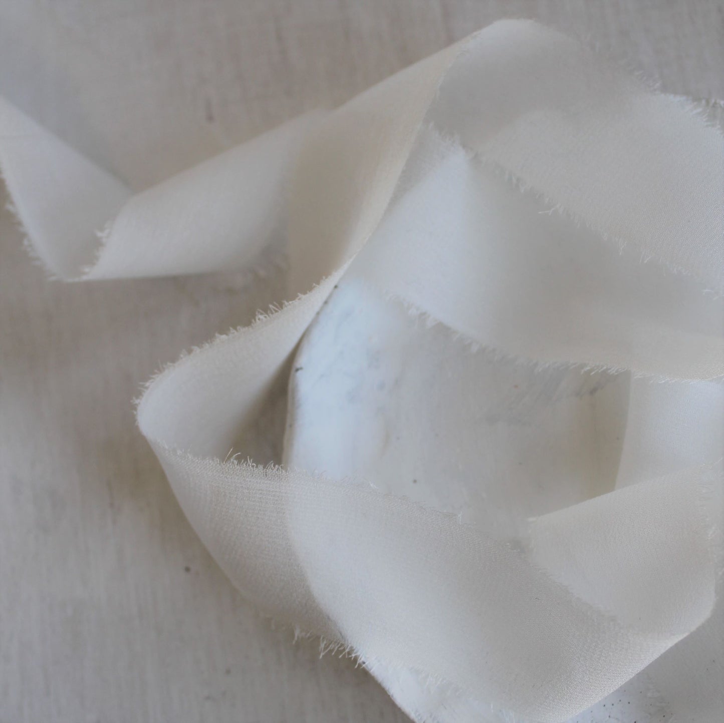 close up of Translucent white silk ribbon styled for flatlays