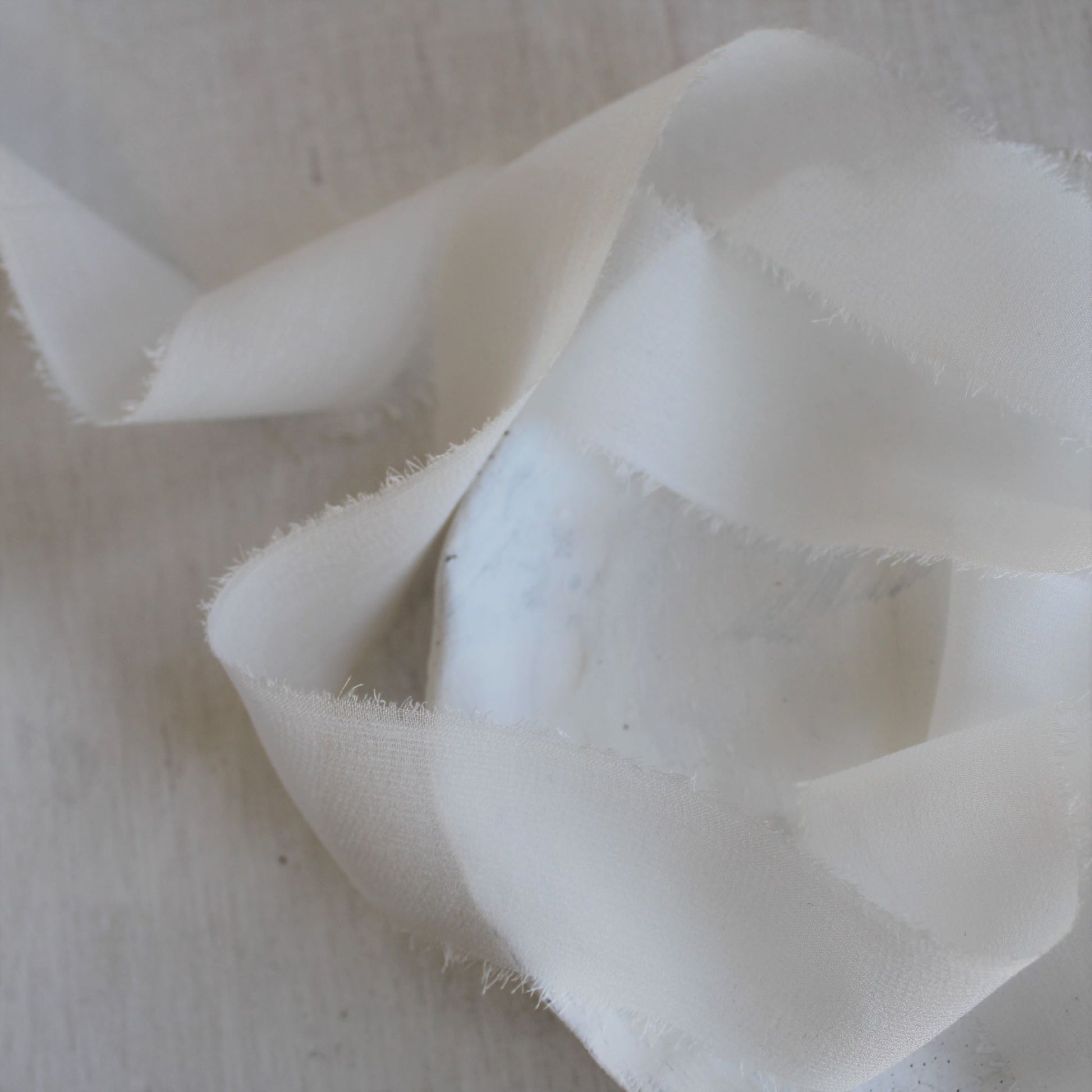 close up of Translucent white silk ribbon styled for flatlays