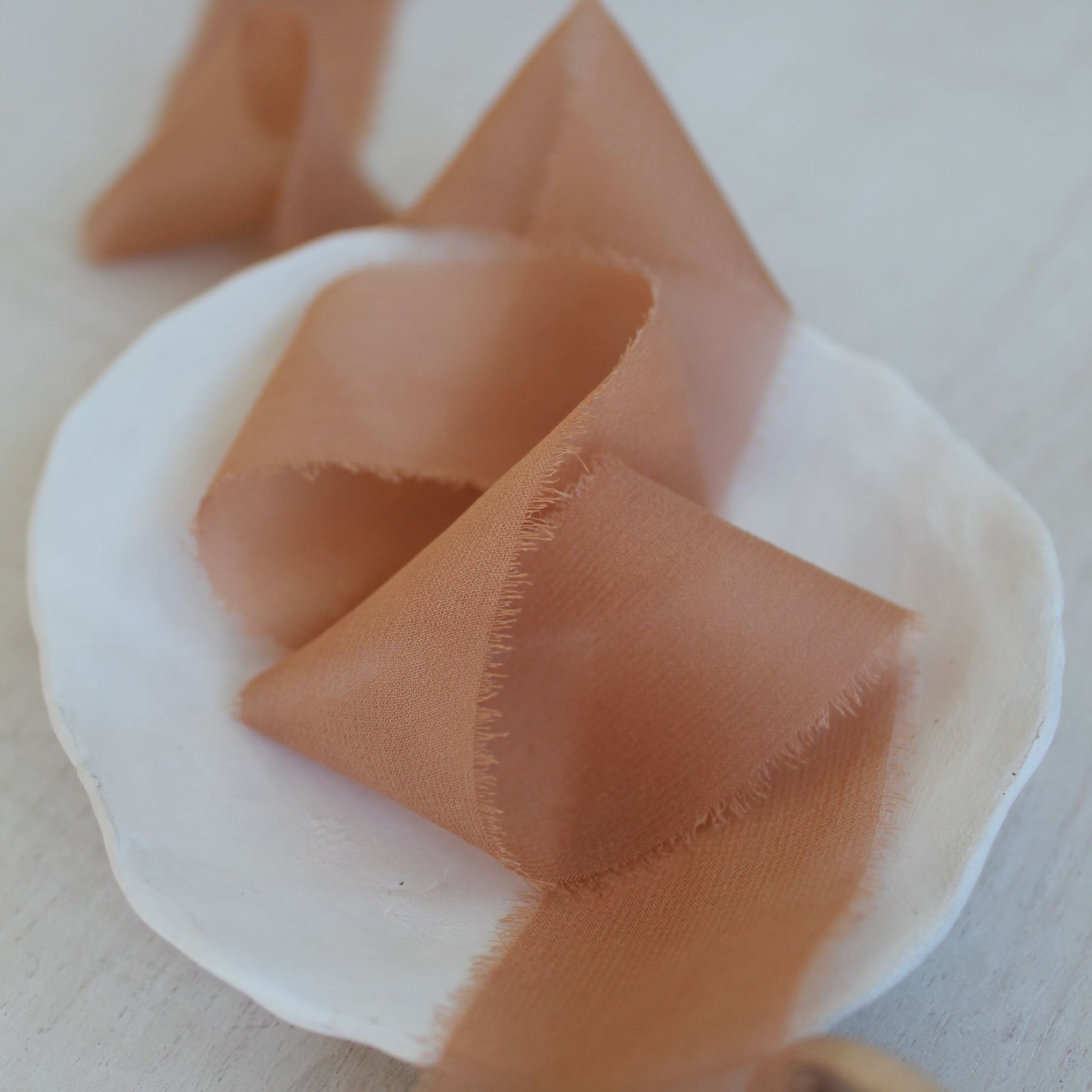 Close-up of feathered edge on chiffon ribbon in terra cotta