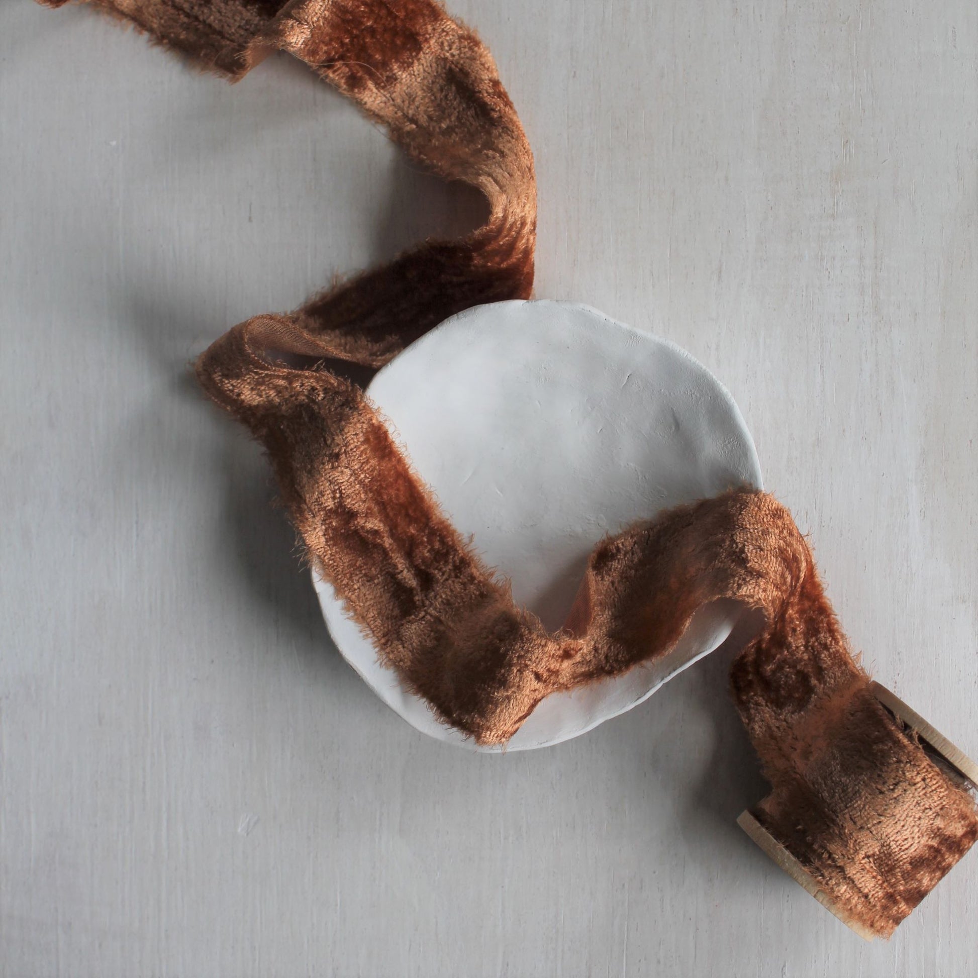 Terra cotta velvet ribbon draped across neutral surface