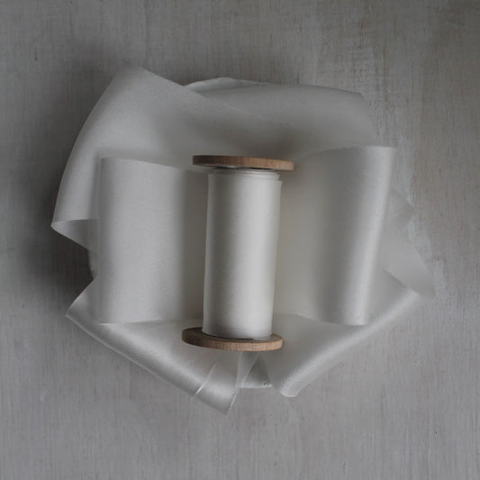 White bias cut silk charmeuse ribbon on wood spool