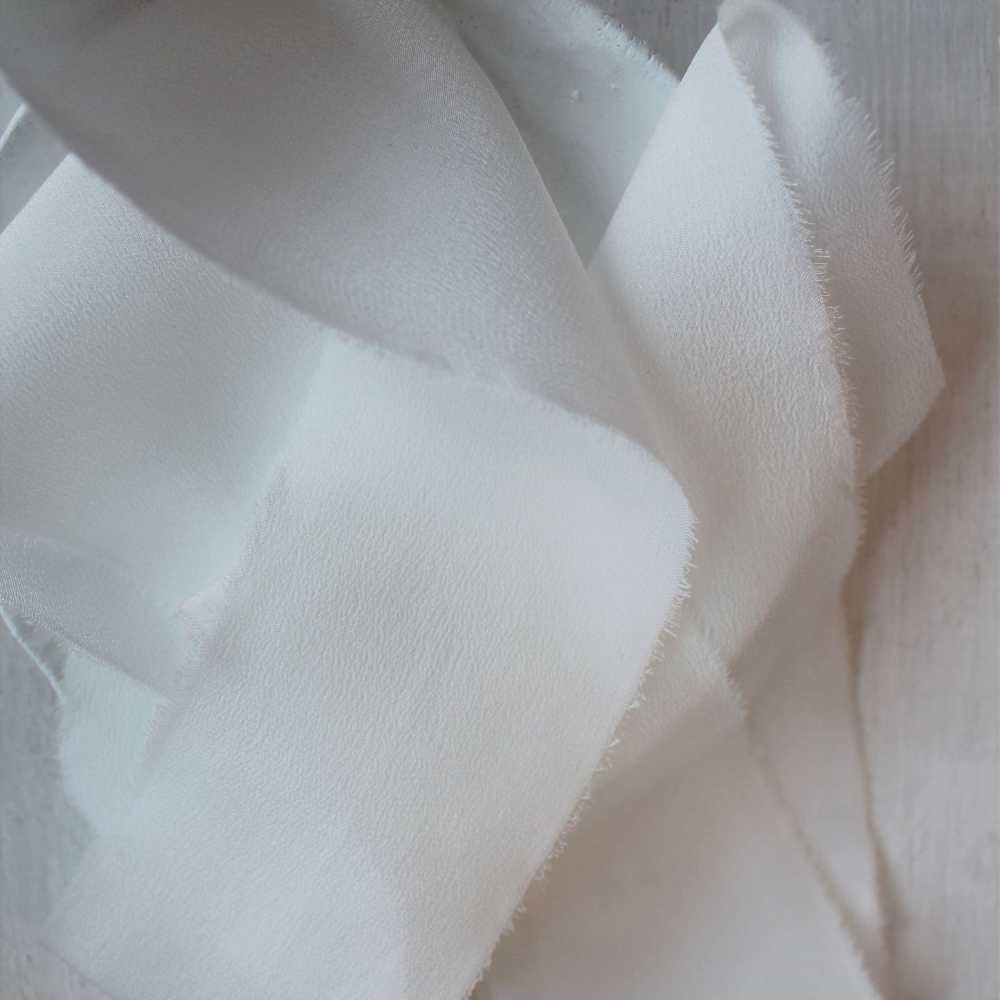 Close-up of hand-torn edges on white silk ribbon
